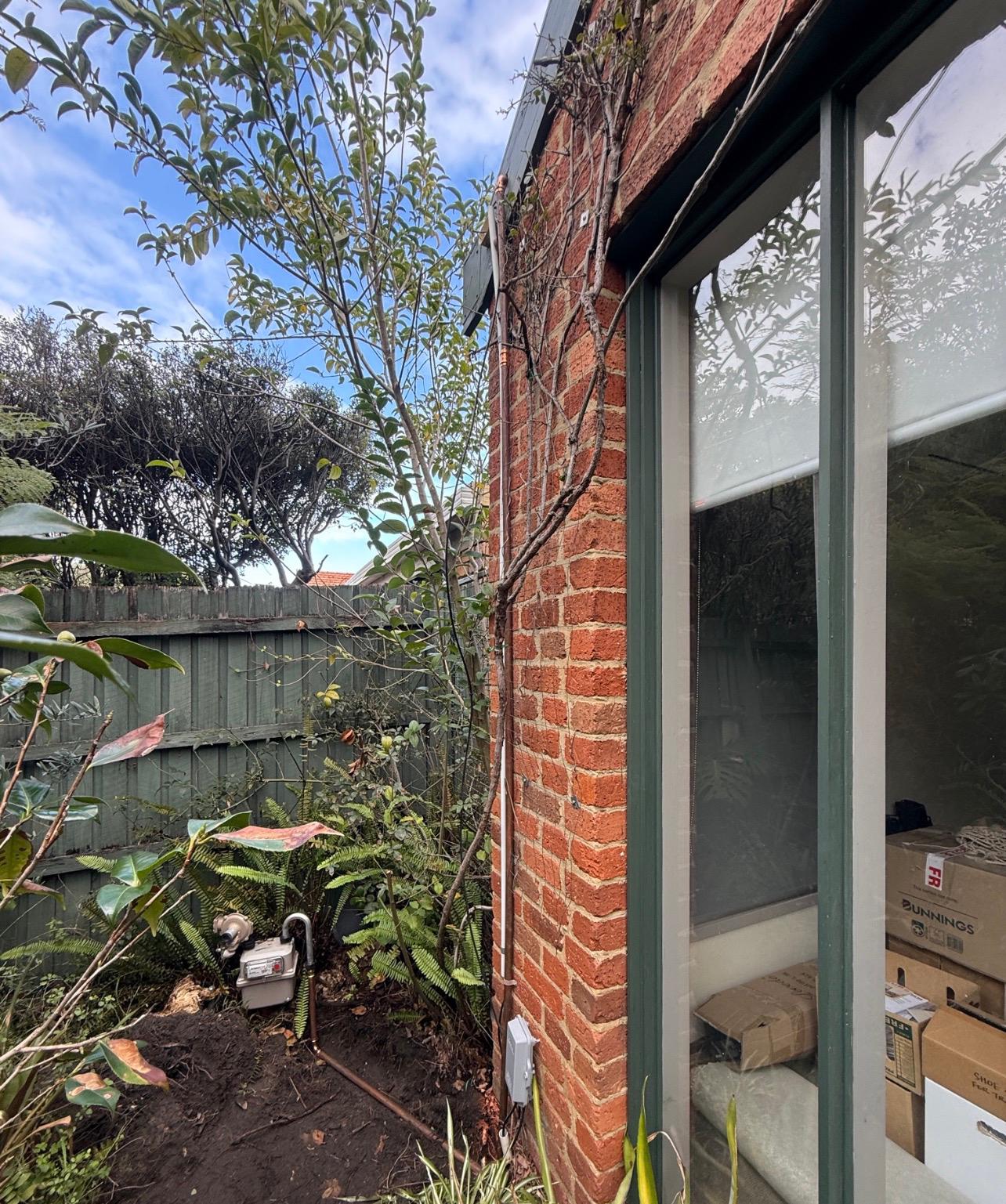 Exterior brick wall showing gas pipe run at Epping property where partial gas renewal was completed